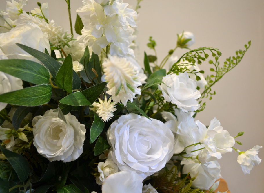 Joy Mini Centrepiece - Detail A bouquet of white flowers including roses, lilies, and greenery.