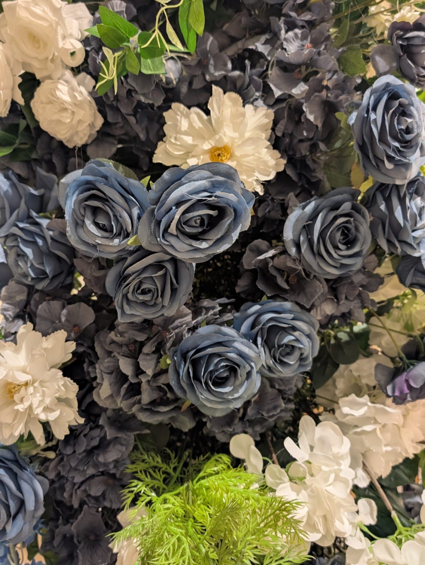 Isabella - Detail Arrangement of dark roses and light flowers with green foliage.