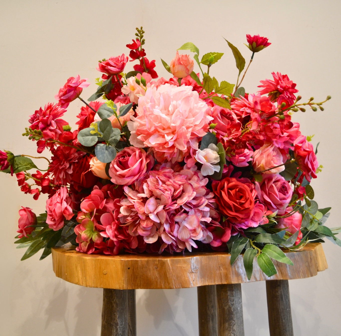 Edith Mini- Close Up A vibrant arrangement of pink and red flowers in a rustic wooden container.