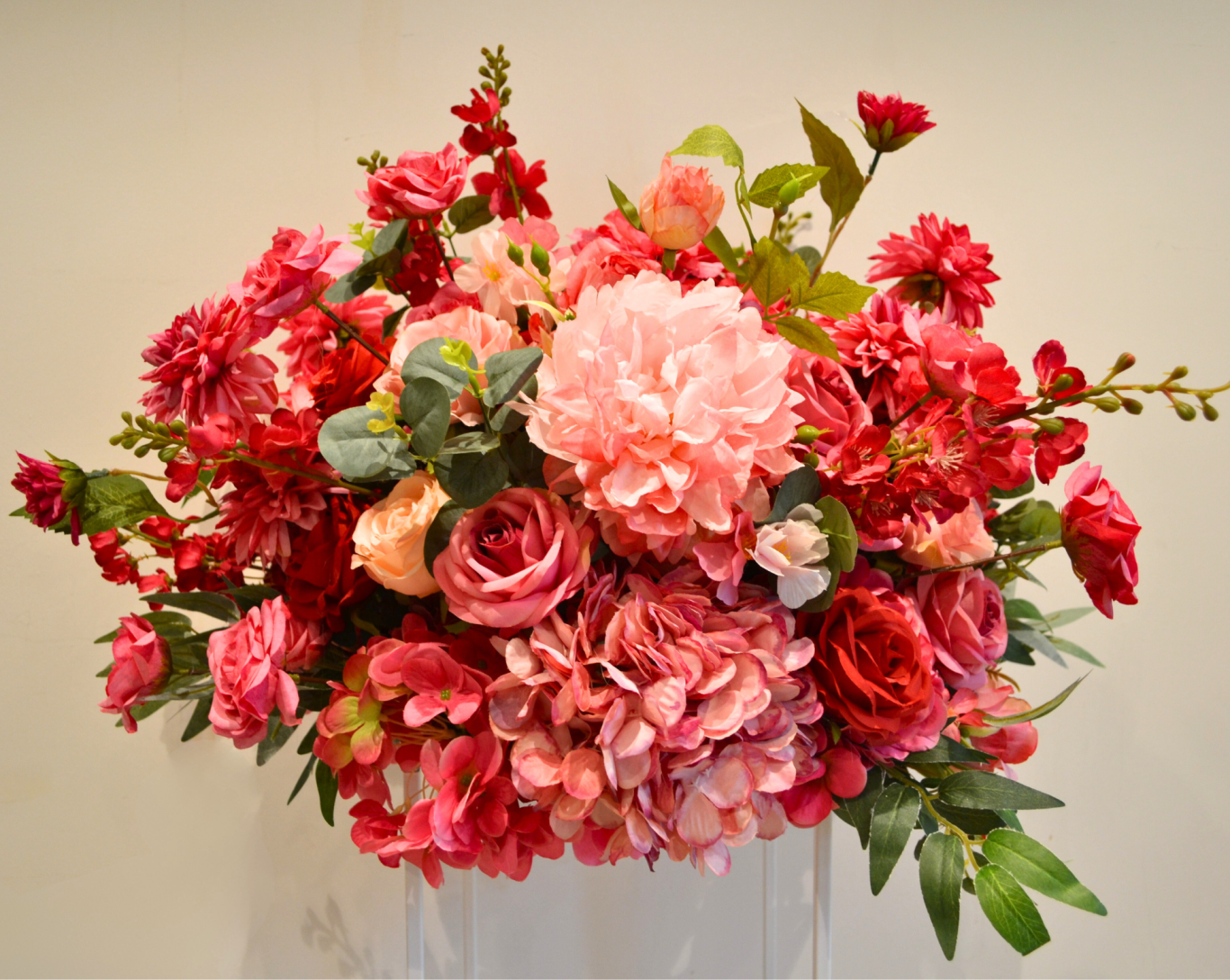 Edith Mini- Close Up A vibrant bouquet of pink and red flowers with lush green foliage.