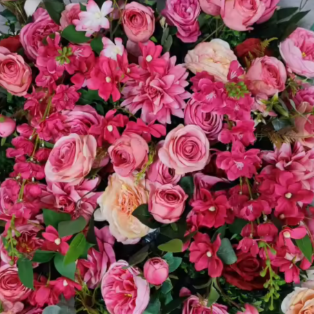 A vibrant arrangement of pink and red roses with assorted flowers and green foliage.