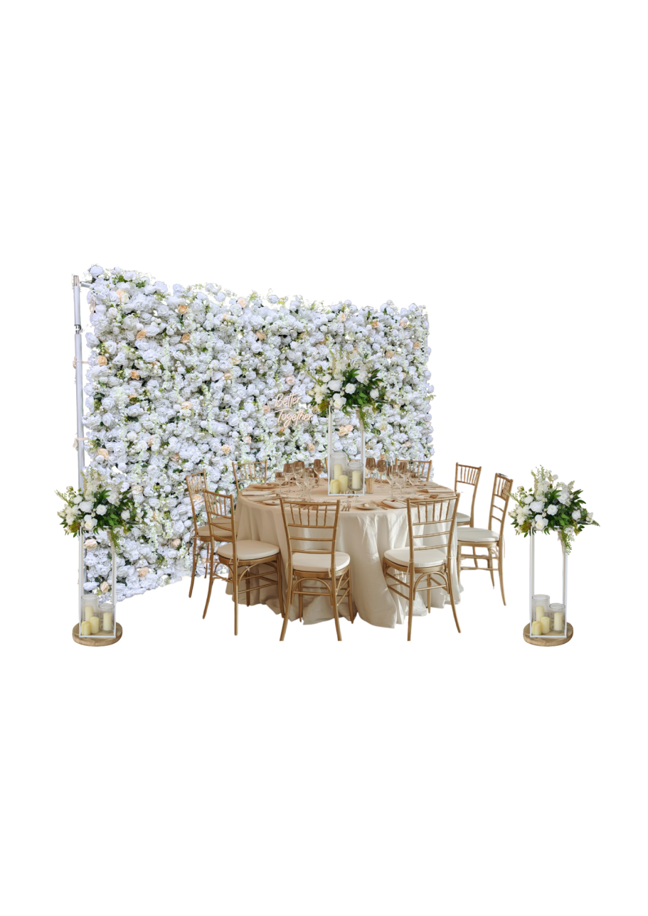 Large Flower Wall Joy with Matching Centrepieces Elegant dining setup with a floral backdrop, gold chairs, and decorative table arrangements.