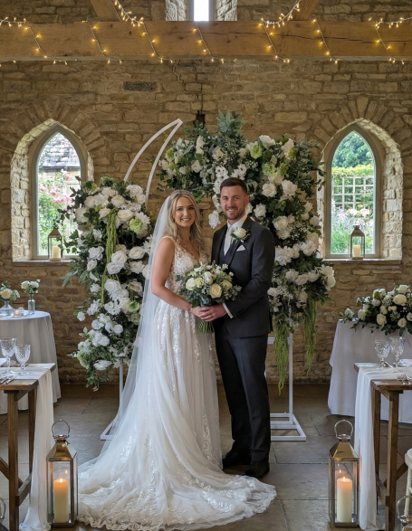 Bride and groom smiling together in a decorated venue surrounded by flowers.