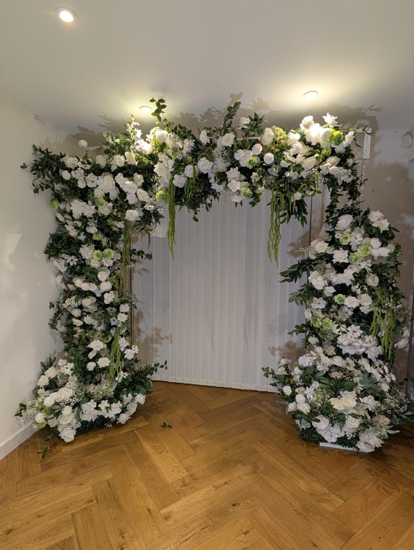 Grace - Boho Frame Floral archway decorated with white flowers and greenery in a bright interior.