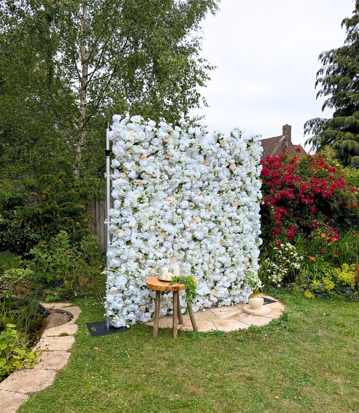 Joy - Size: Regular A floral backdrop in a garden, with a stool and greenery nearby.