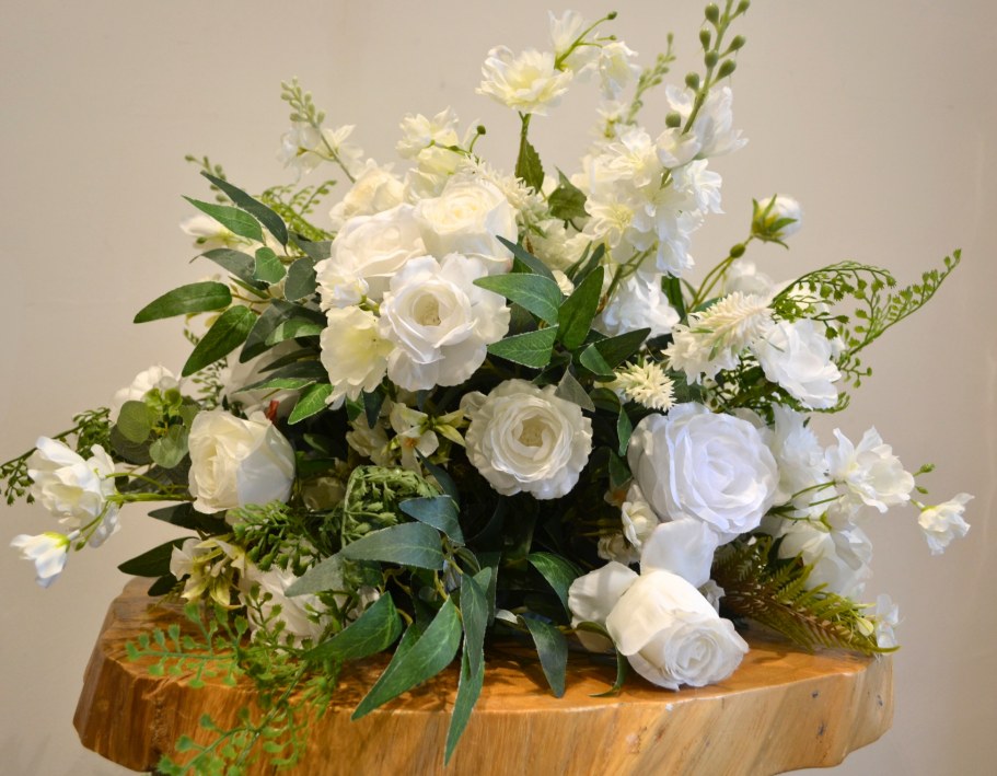 Joy Mini Centrepiece - Detail A bouquet of white flowers, including roses and lisianthus, arranged with green foliage.